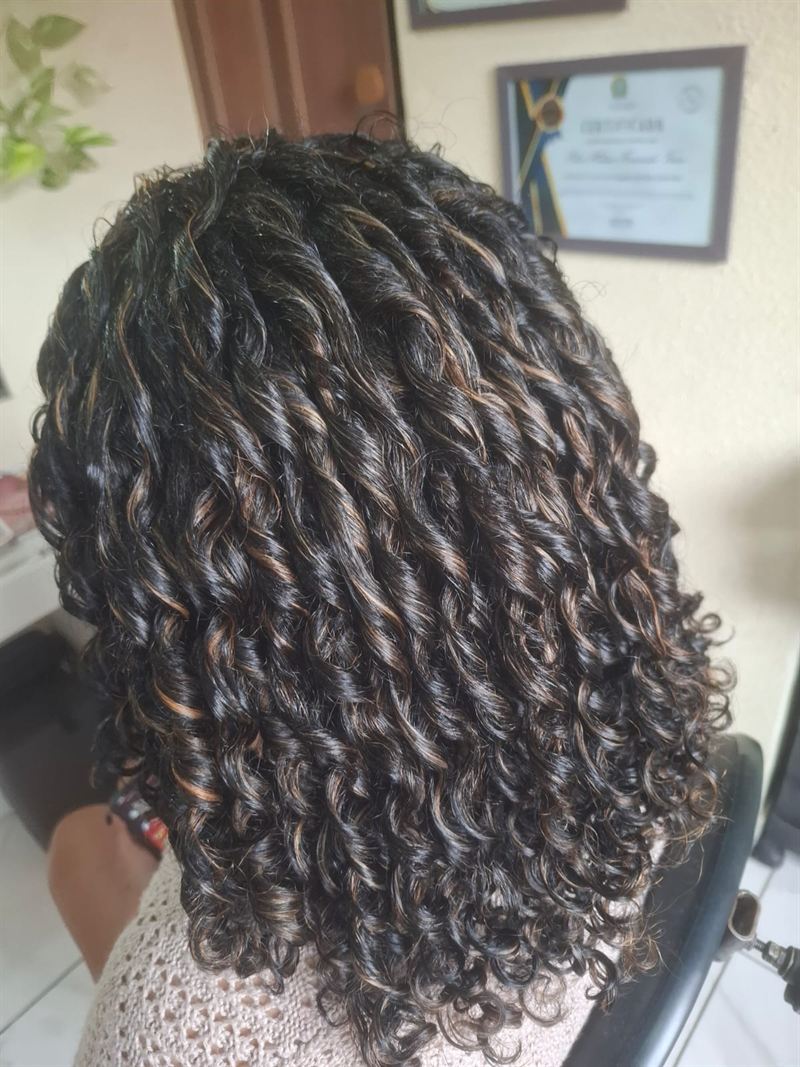 Cachos definidos em cabelo escuro com reflexos acobreados, finalizados no Studio Helena Fernandes em Manaus